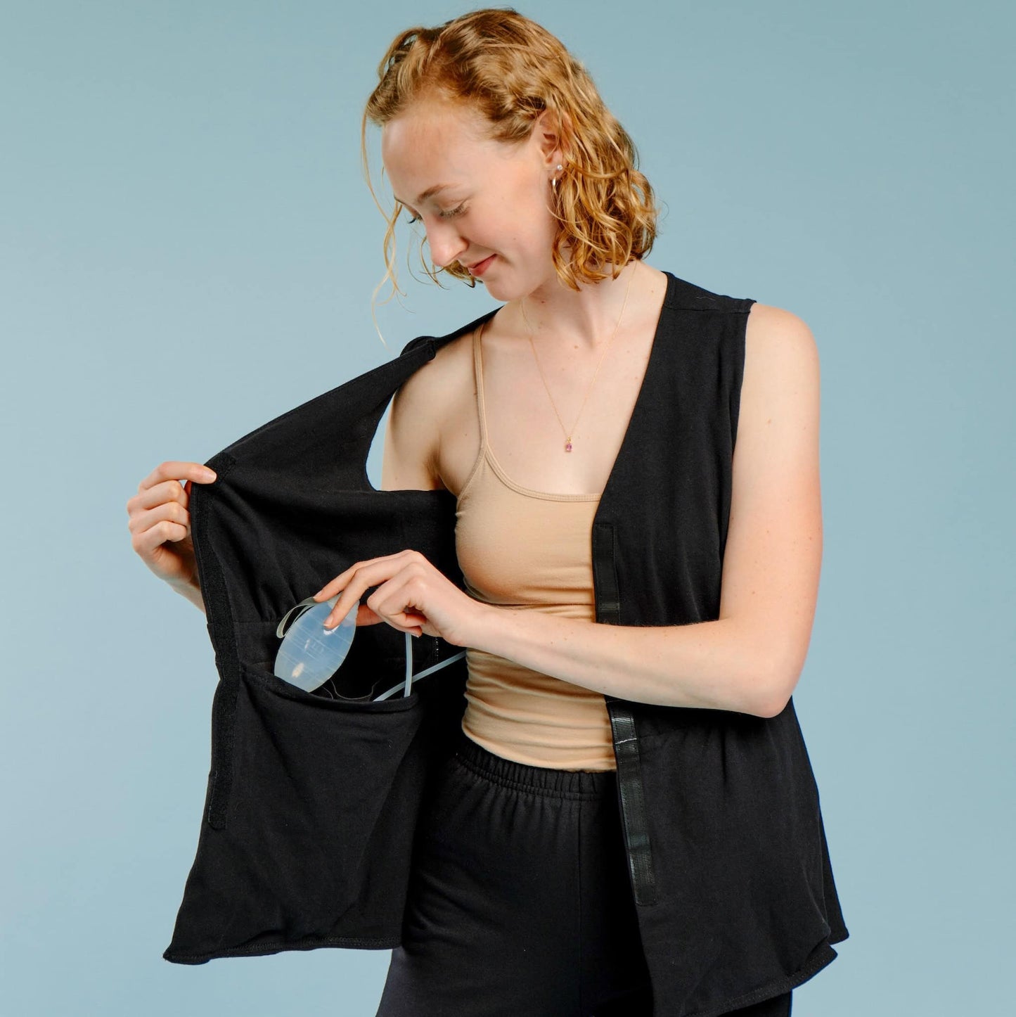 Woman placing post-surgery drains into a waterproof pocket, inside of shirt.
