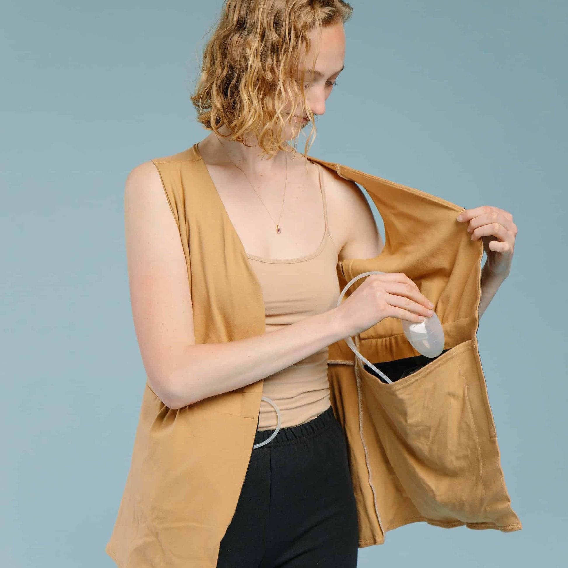 Interior view of a mastectomy camisole, with model placing post-surgery drains into a black waterproof pocket.