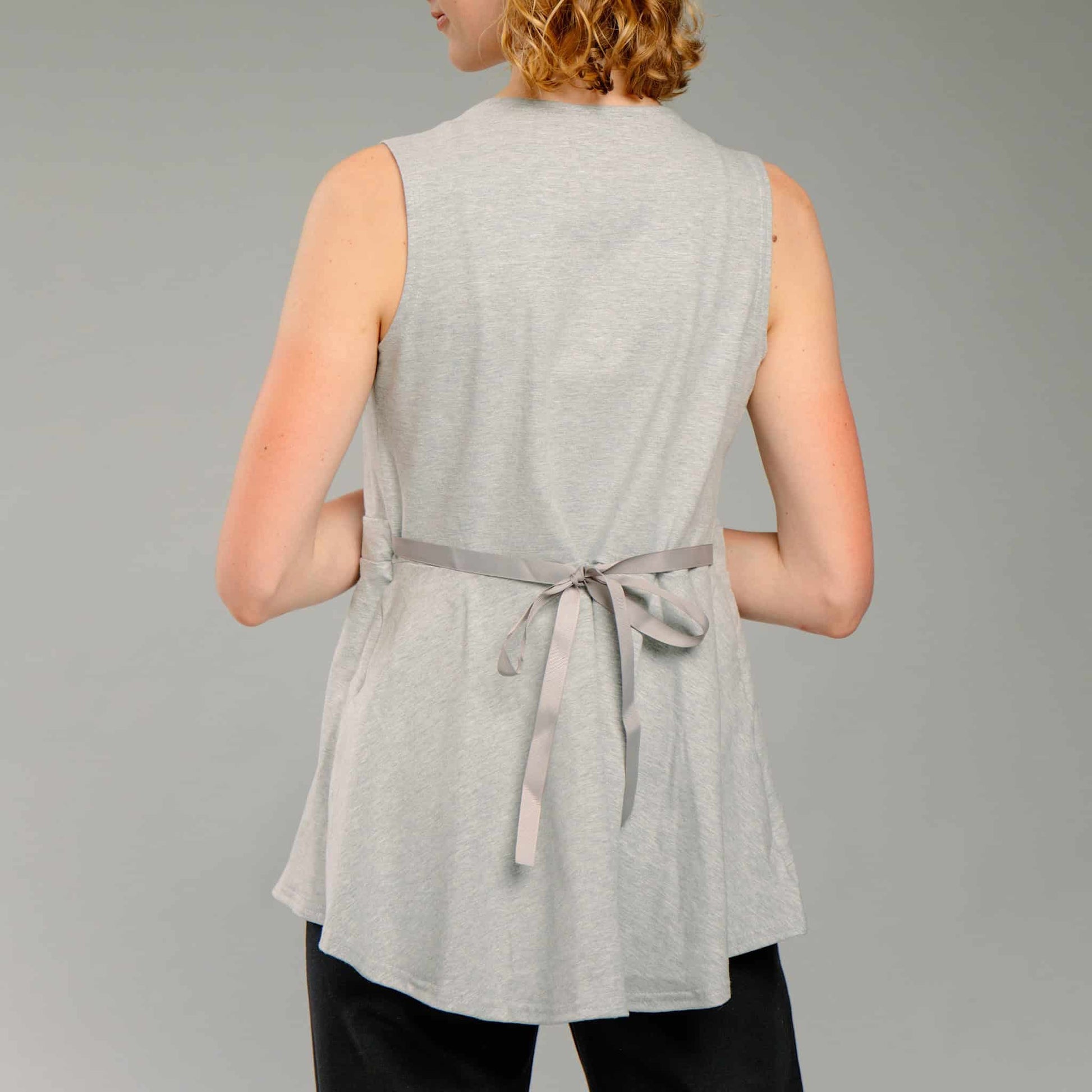 Back view of woman wearing a light heather gray sleeveless top, with an adjustable ribbon tied in a bow.