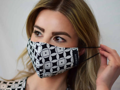 Blonde woman wearing a black and white geometric patterned face mask.