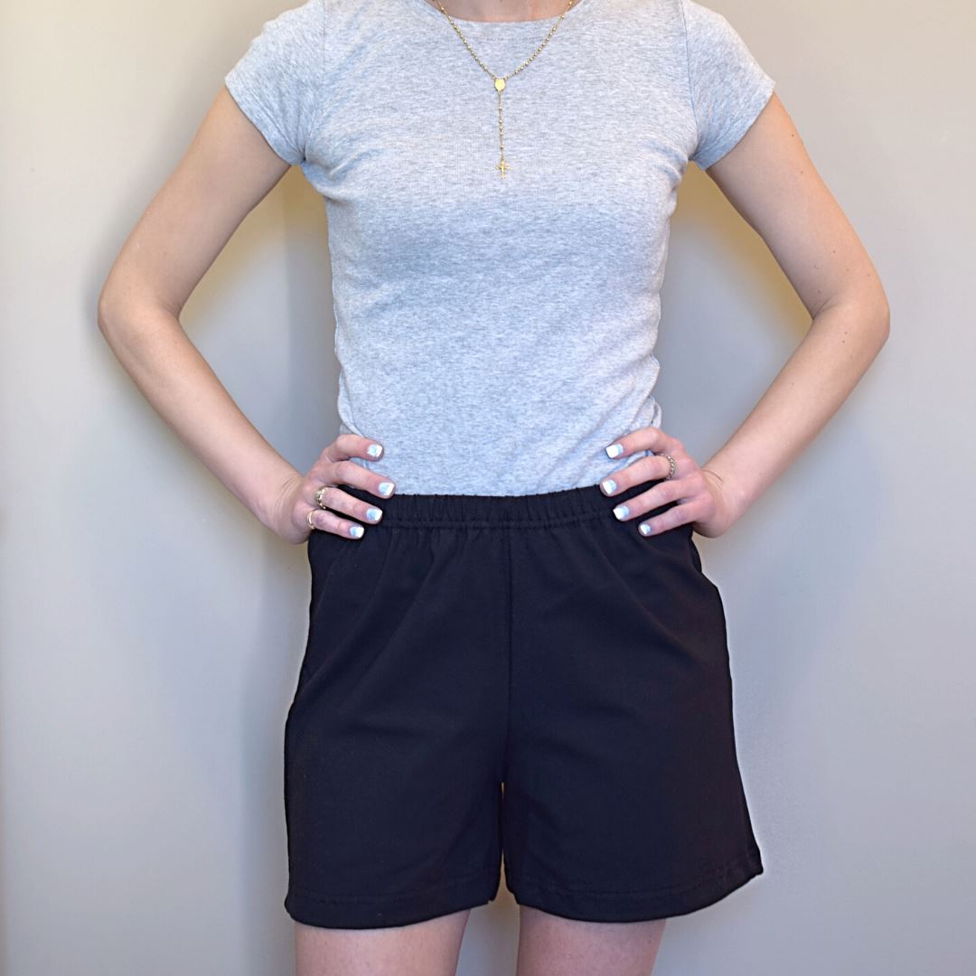 Woman with hands on hips wearing black elastic-waist shorts.Liz 