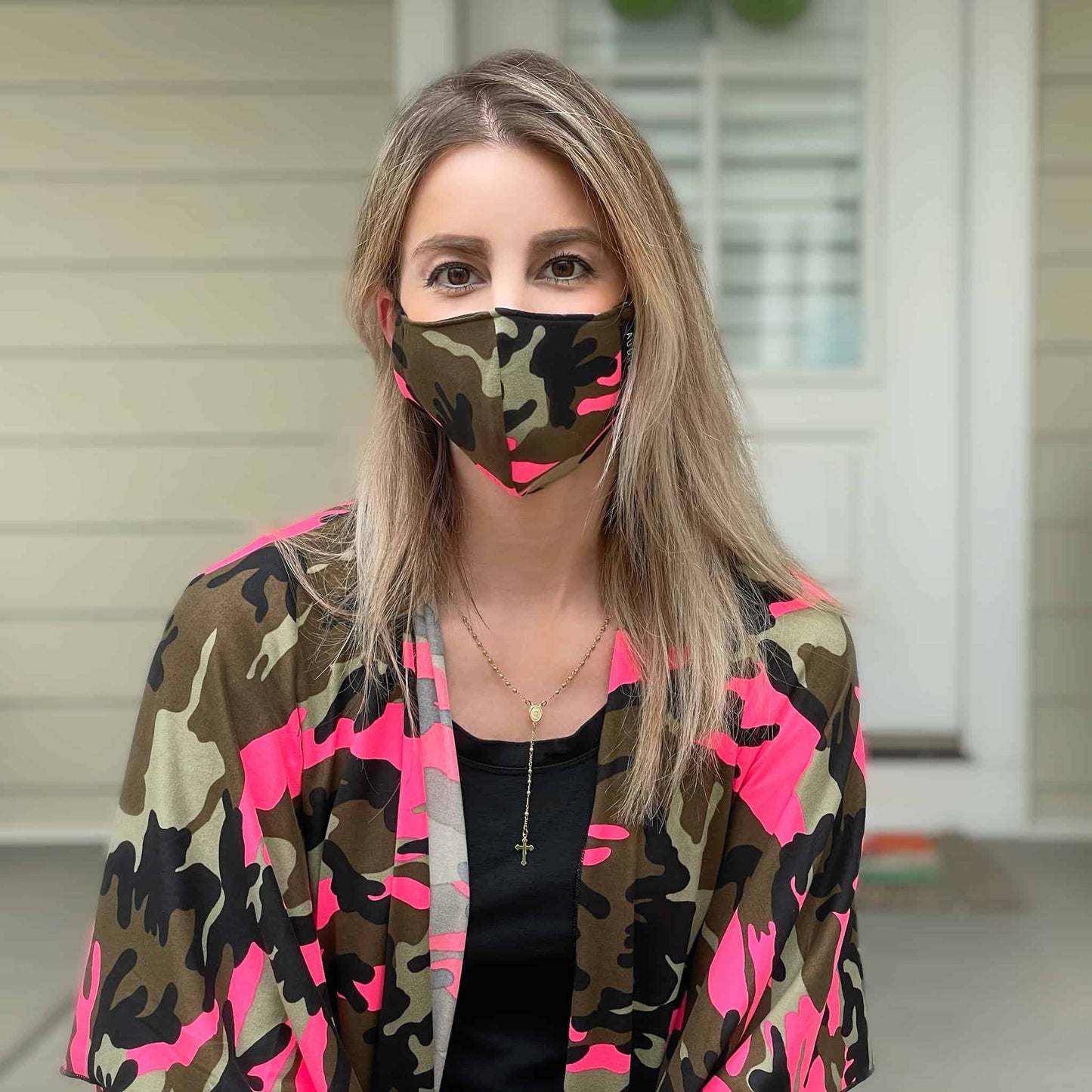 Woman wearing a pink camo face mask with a matching lightweight shawl on shoulders.